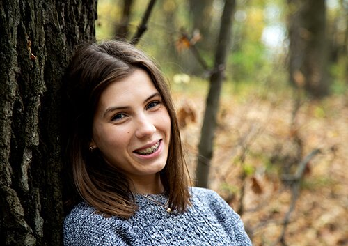 Young beautiful girl with braces on her teeth in a gray sweater